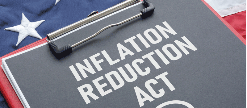 the words inflation reduction act printed on paper on a clipboard sitting on an american flag